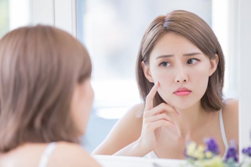 鏡を見ながら肌の悩みを確認する女性